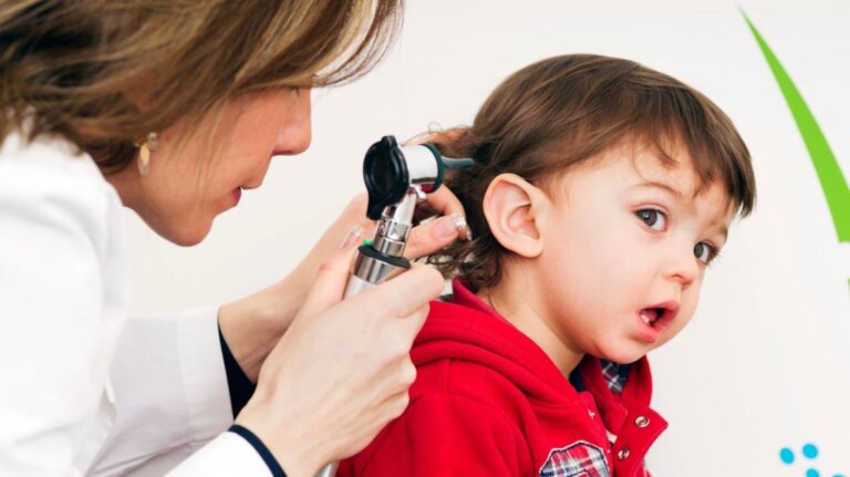 Child in red shirt getting ear examined with an otoscope by a healthcare professional